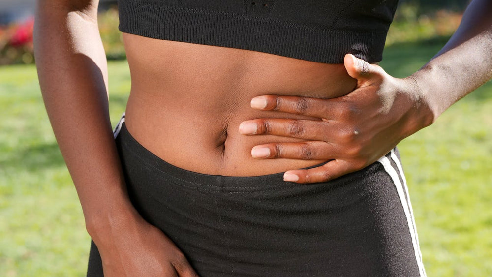 An image of a woman holding the side of her stomach because of pain or discomfort.