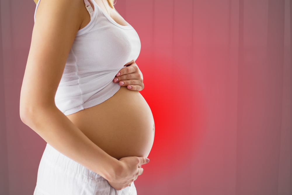 An image of a pregnant woman, in a red light background.
