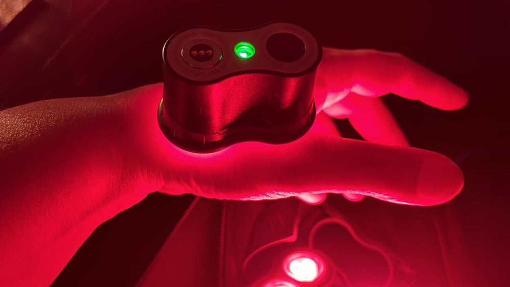 A red light therapy device on someone's hands.