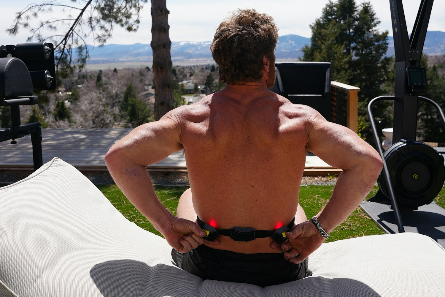 An image of a man using red light therapy device on his lower back to alleviate lower back pain.