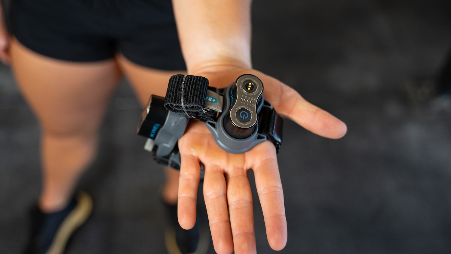 Image of a hand with red light therapy device from Kineon, the Move + Pro.