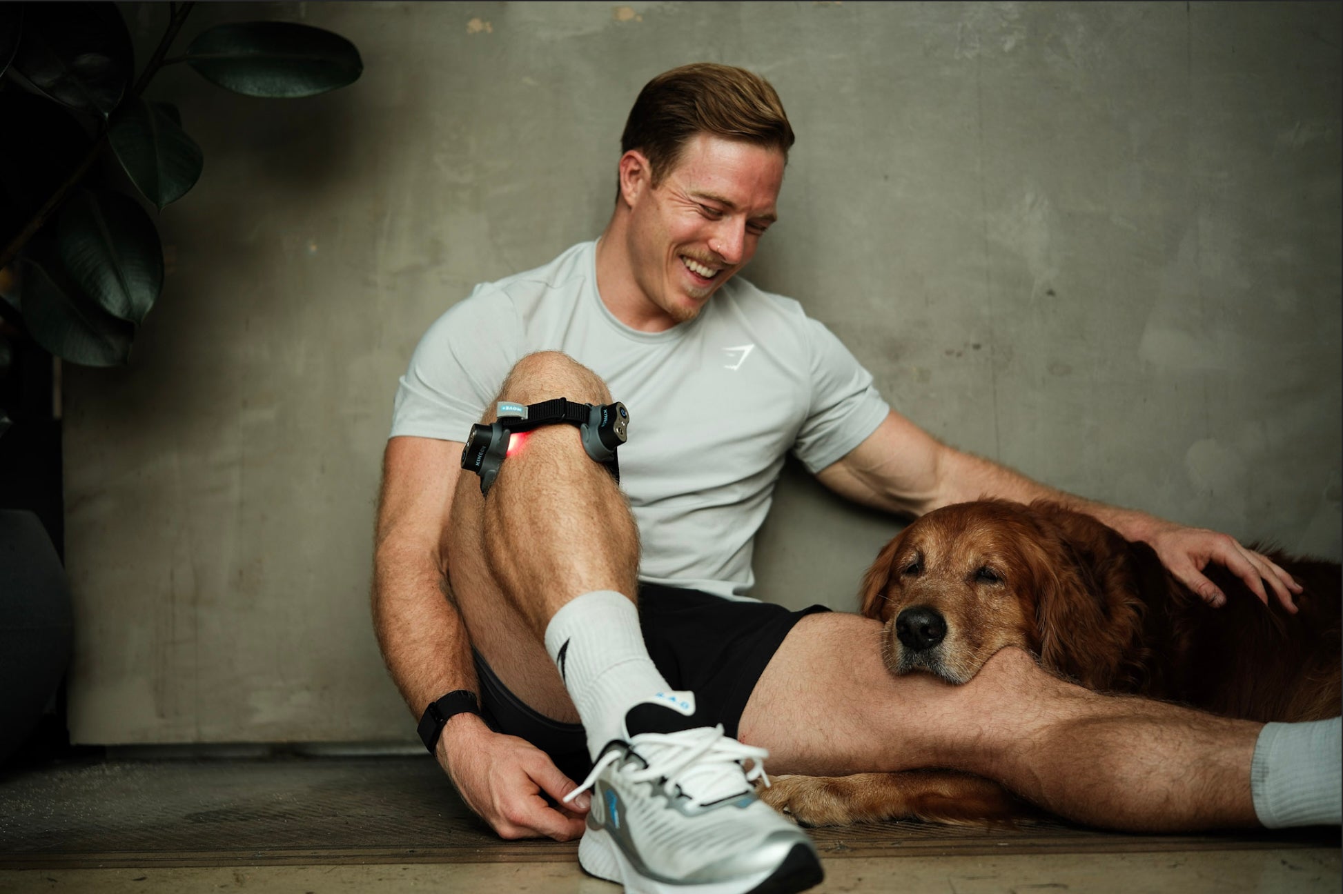 Noah Ohlsen sitting and relaxing with his dog and wearing the Move+ Pro red light therapy device while habit stacking.