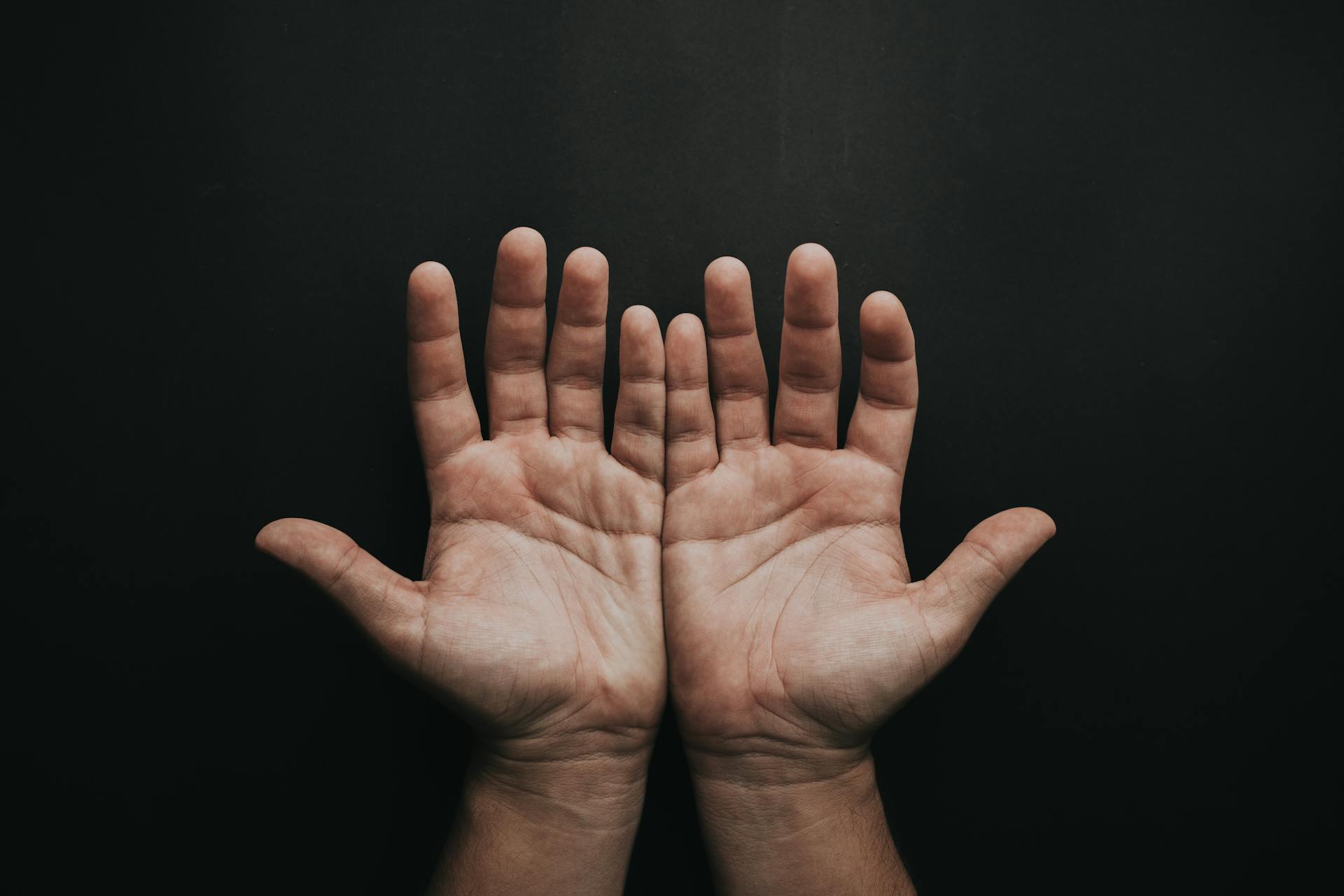 An image of open hands in a black or dark background.