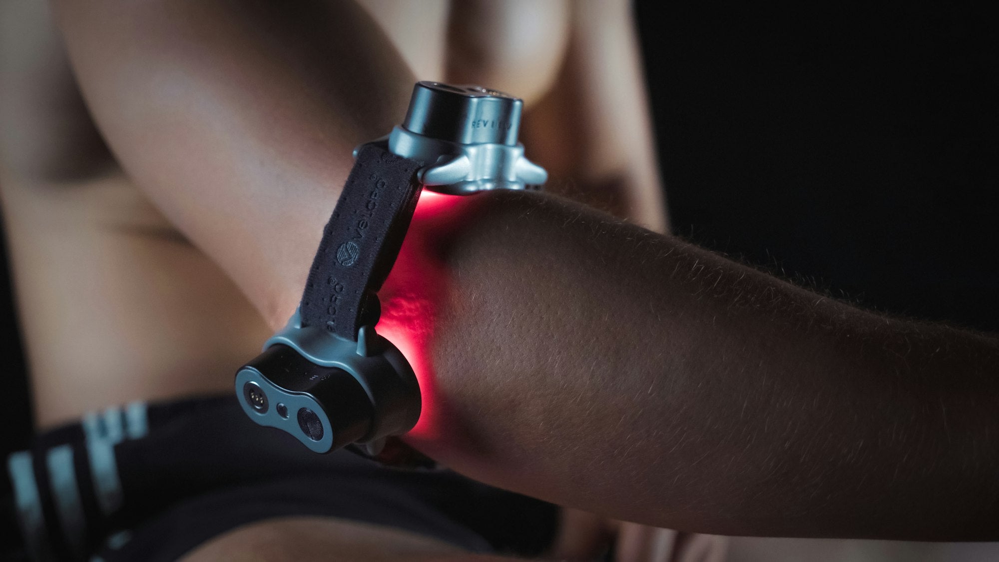 A man's elbow with red light therapy device.