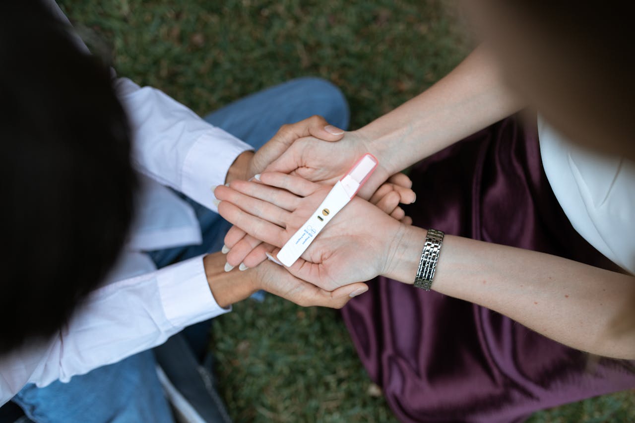 A man and woman holding the positive pregnancy test in their open palms.